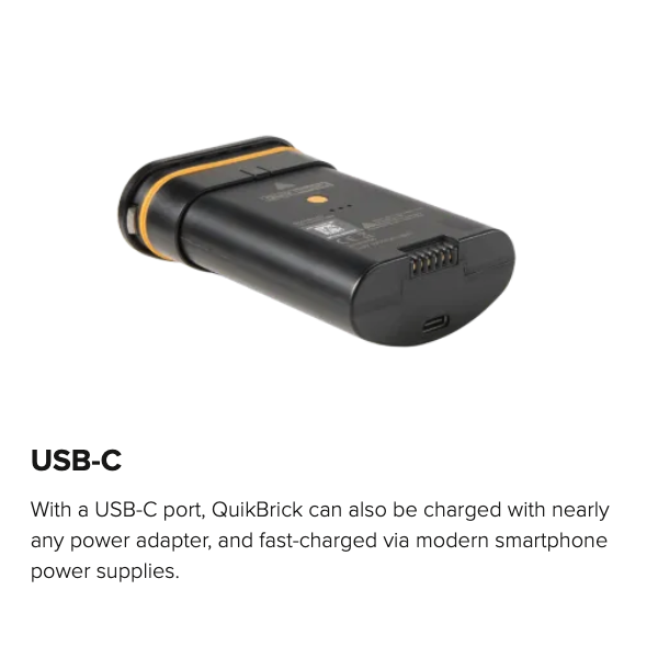 Astera QuikBeam QuikBrick battery showing USB-C charging port angle view marketing graphic with text overlay black unit with orange accent band transparent background