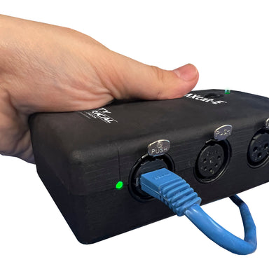 City Theatrical DMXcat-E held in hand side view showing Ethernet port with blue cable XLR connectors push button and green LED indicator white background