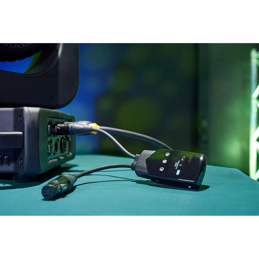 LumenRadio MoonLite 2 wireless DMX CRMX transceiver in use on set connected to lighting fixture via XLR cable with green stage lighting in background lifestyle promotional shot