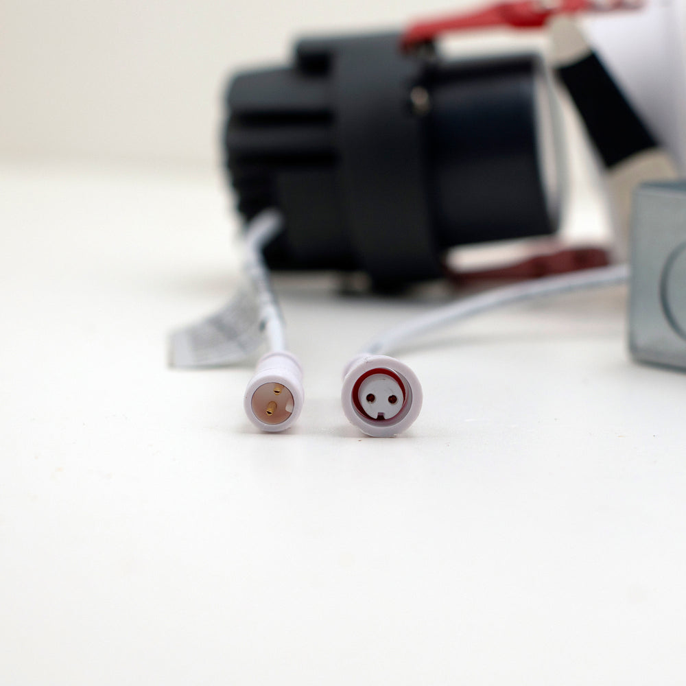Moss LED 3-Inch Recessed Downlight Dim-To-Warm close-up of quick-connect cable connectors showing male and female pin configurations white circular plugs with downlight body blurred in background