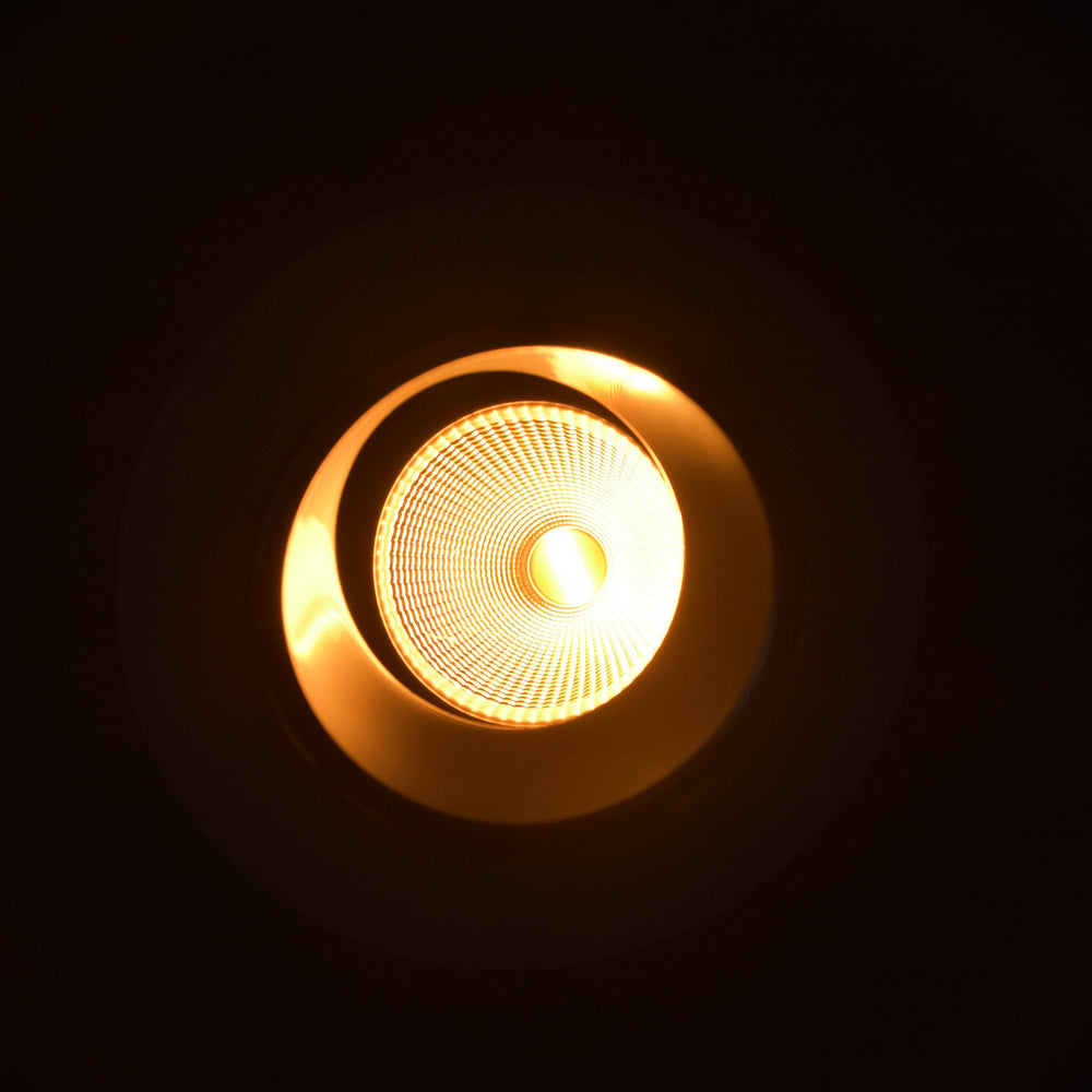 Moss LED 3-inch recessed downlight dim-to-warm illuminated with warm amber glow, below view looking up into reflector cone with LED center, dark background