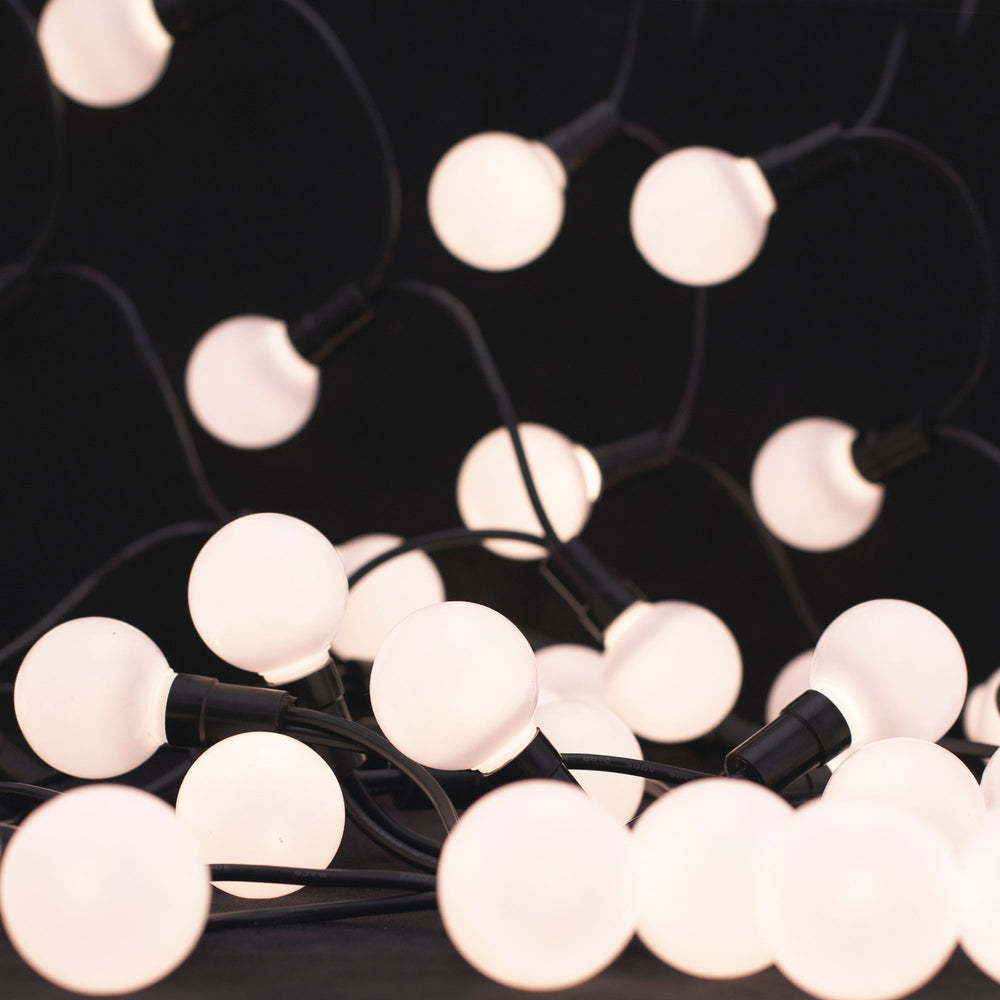 Moss LED globe LED string lights warm white frosted round bulbs close-up illuminated showing decorative patio and event lighting on dark background
